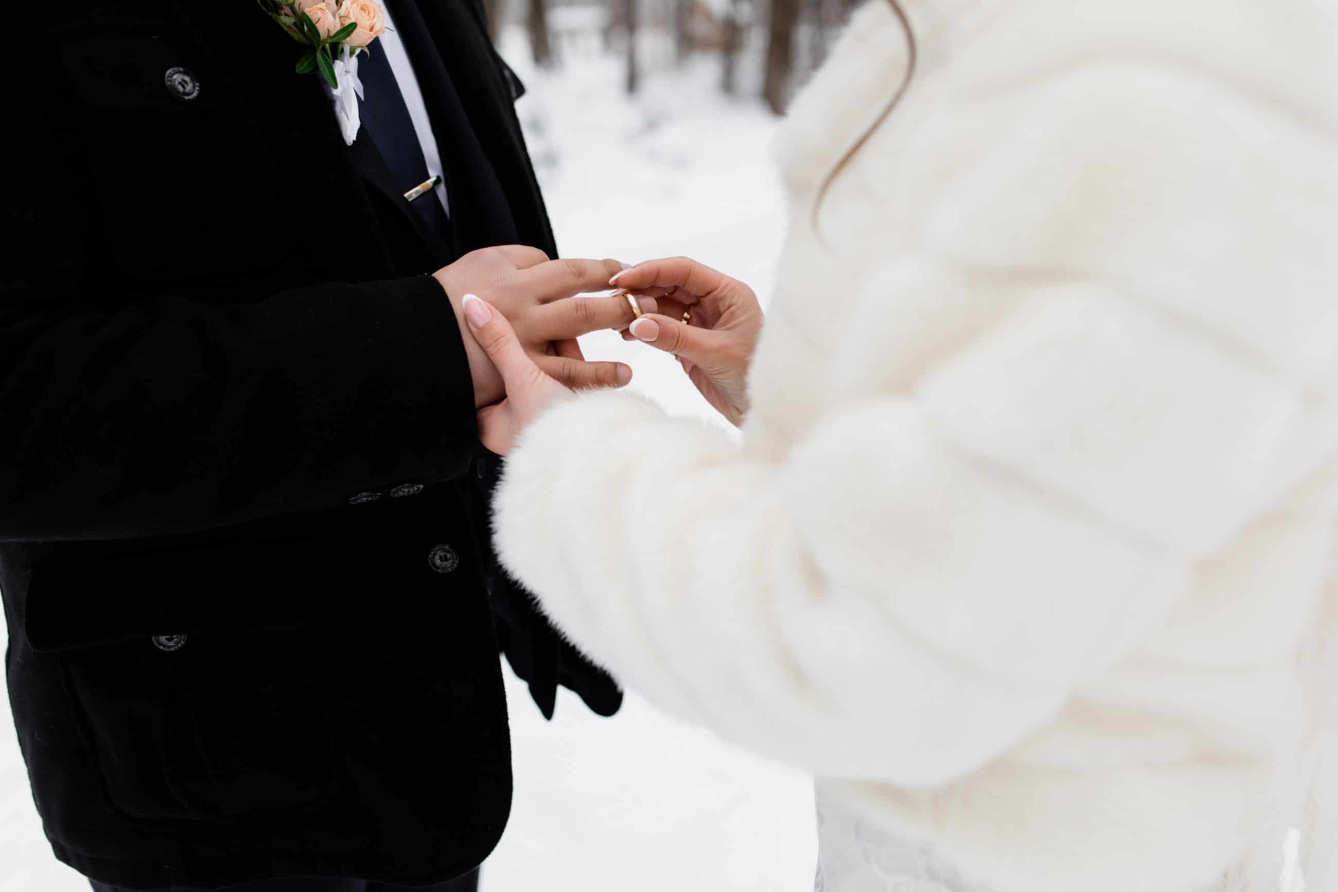 Winterhochzeit Braut steckt Ehering an Bräutigam Hochzeitsplaner München